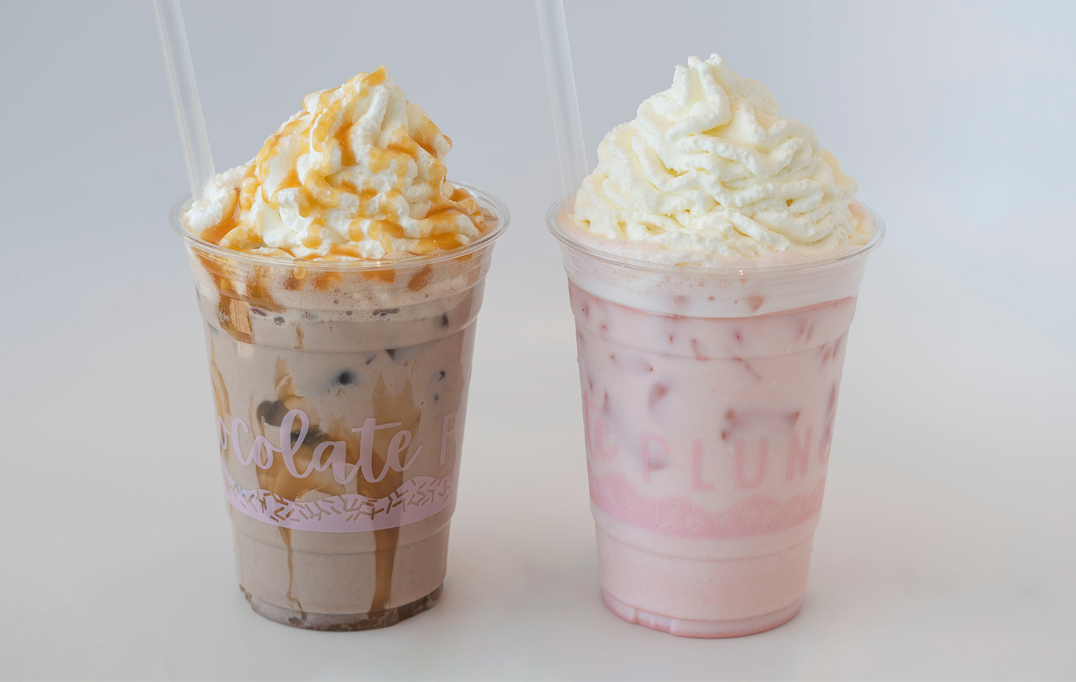 iced chocolate milk and iced raspberry milk both topped with whipped cream